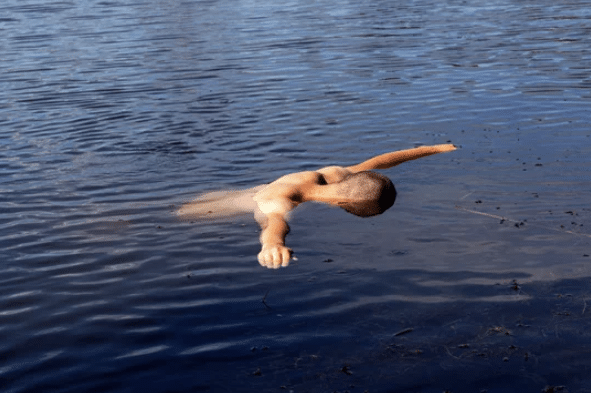 Screenshot 2026-03-06 133601 - N9BO℠ | Global Underwater Services Ltd A person is floating face-down in calm water with one arm stretched forward and the other by their side, creating gentle ripples on the water's surface.
