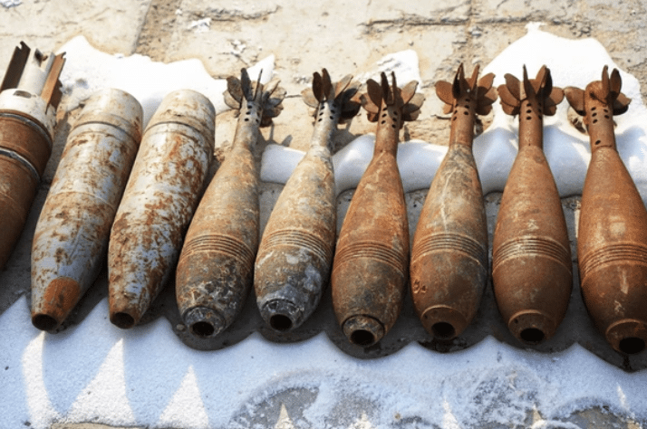 Screenshot 2026-03-14 at 161501 - N9BO℠ | Global Underwater Services Ltd Several rusted and weathered mortar shells are lined up on a rough surface outdoors, some with visible tail fins, showing signs of age and corrosion.