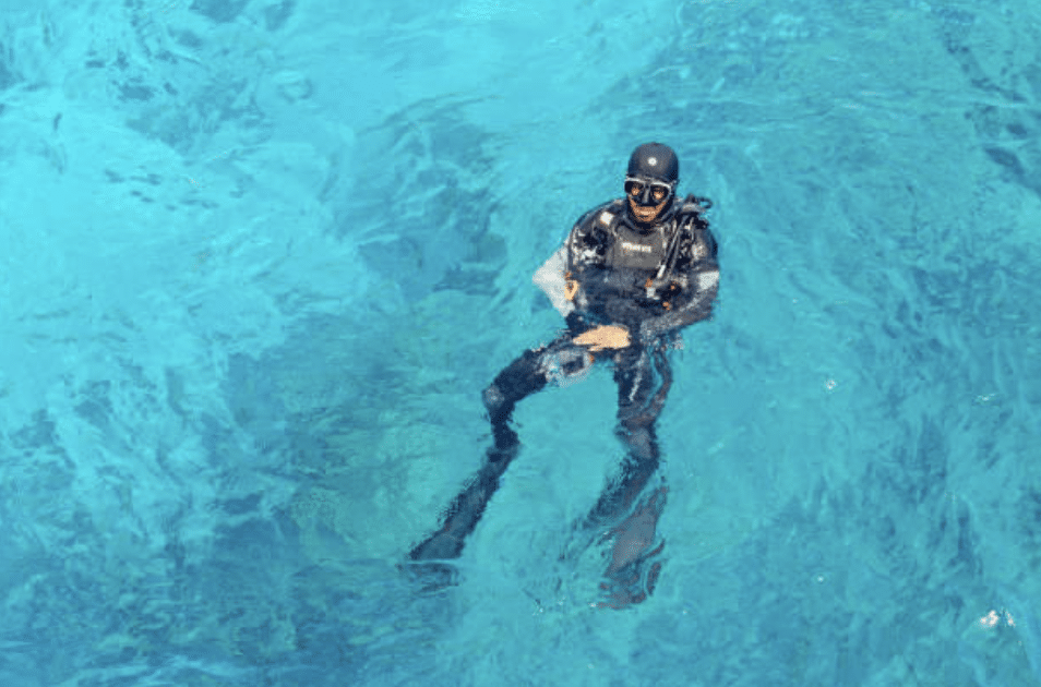 Screenshot 2026-03-16 at 010802 - N9BO℠ | Global Underwater Services Ltd A scuba diver wearing a black wetsuit, mask, and fins floats on the surface of clear, bright blue water.