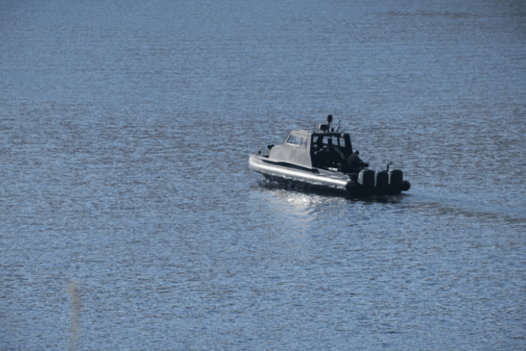 Screenshot 2026-03-30 at 165140 - N9BO℠ | Global Underwater Services Ltd A black inflatable boat with a cabin and equipment on its roof moves across calm blue water under a clear sky.