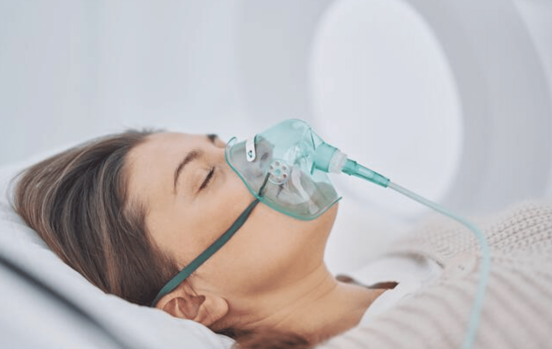 Screenshot 2026-04-05 at 195531 - N9BO℠ | Global Underwater Services Ltd A woman lies in a hospital bed with her eyes closed, wearing an oxygen mask connected to tubing.