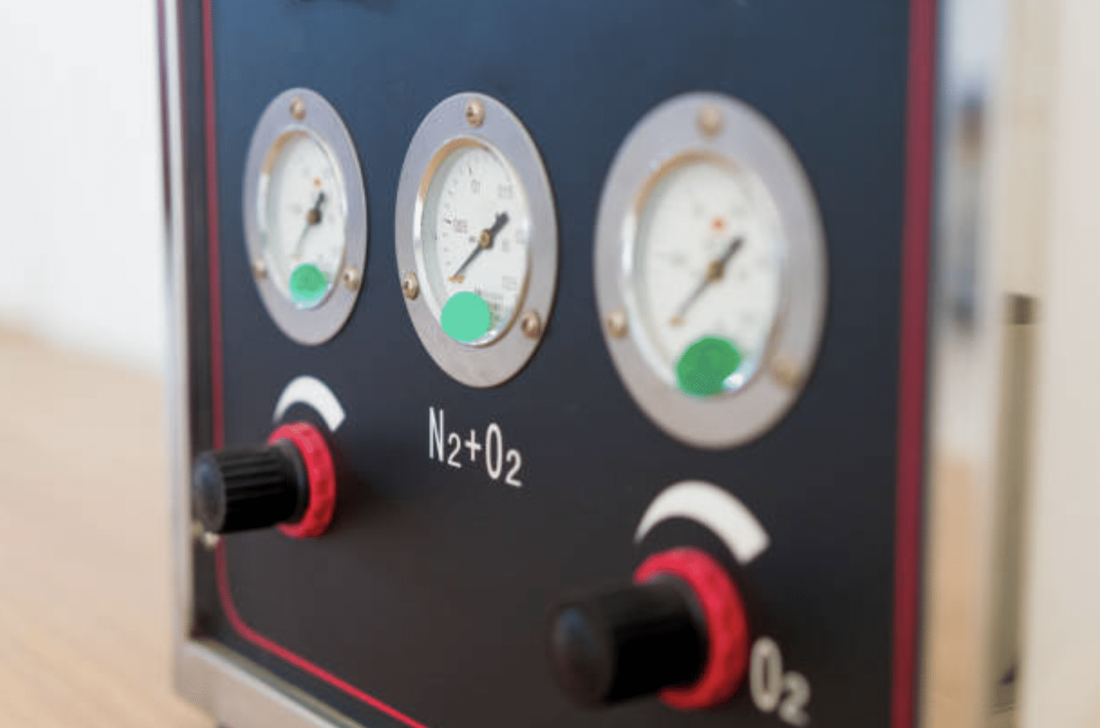 Close-up of a control panel with three pressure gauges and two black knobs labelled “N2+O2” for a nitrous oxide and oxygen delivery system, often used in medical or dental environments.