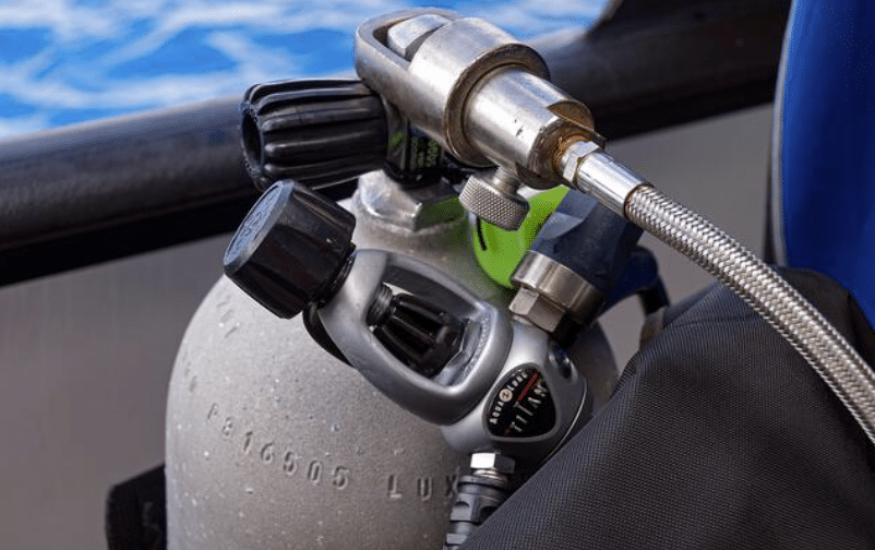Screenshot 2026-04-24 103347 - N9BO℠ | Global Underwater Services Ltd Close-up of a scuba diving cylinder with attached regulator and pressure gauge, placed on a boat near water.
