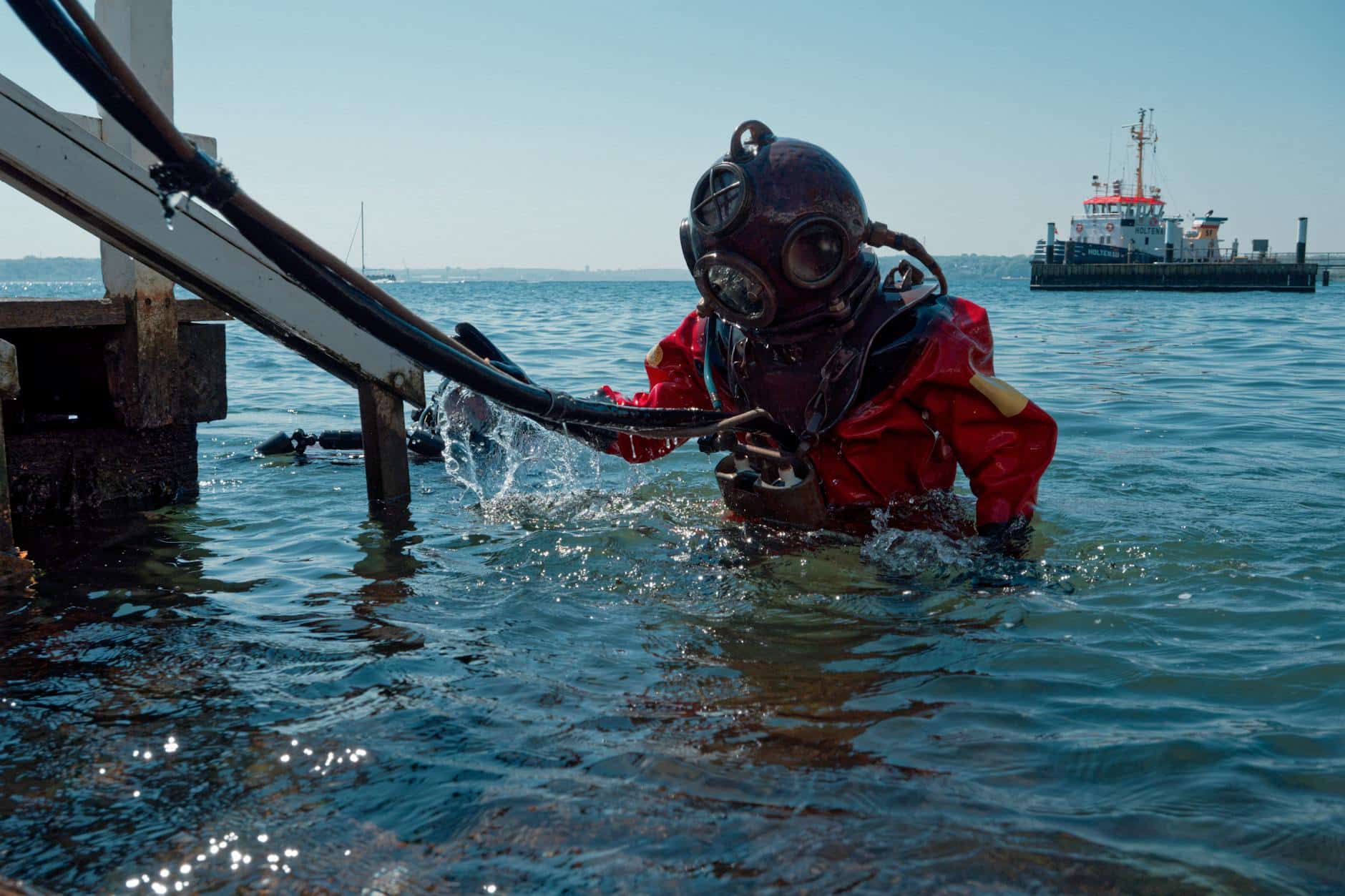 pexels-photo-20481591 - N9BO℠ | Global Underwater Services Ltd diver in a red standard diving dress with a brass helmet coming out of the sea